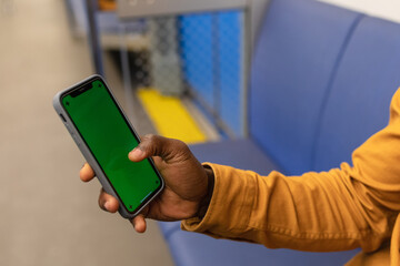 Close-up of the hand of an African-American man with a mobile phone in his hand against the background of public transport