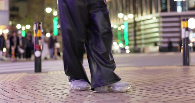 Closeup, feet and person dancing in city, moving body and freedom for street performance in night. Girl, dancer or sneakers for art, concert and steps with creativity, metro road and balance in Tokyo