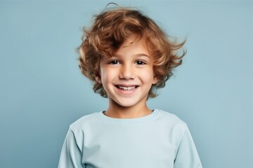 Portrait of a smiling little boy with curly hair over blue background