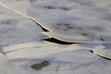Crushed ice flakes on the field with black plowed land