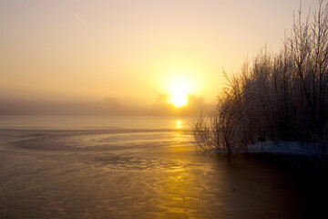 Misty sunrise by the lake with round formations in the ice