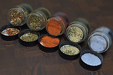 different spices sea salt in small jars on a wooden table