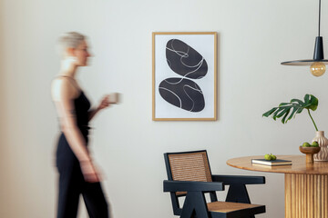 Warm and cozy interior of living room space with mock up poster frame, round table, chairs, pedant...