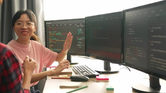 Slow motion back end software developer engineer for computer programming working together on debugging writing computing code, solving complex algorithms display on monitor in office. Burgeoning