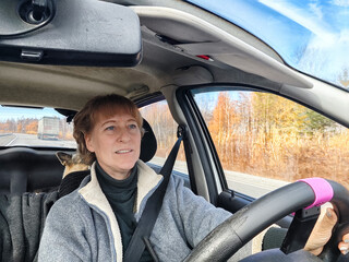 Portrait of female driver in solo journey. Adult mature woman holding steering wheel and looking through windscreen in travel by vehicle on vacation. Lady girl who is owner or rent a car for travel