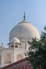 Fototapeta na wymiar Main and smaller marble domes and decorative spires of Taj Mahal mausoleum. View from the Agra city streets. Close up photo, cover book. Agra, Uttar Pradesh, India