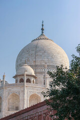 Main and smaller marble domes and decorative spires of Taj Mahal mausoleum. View from the Agra city...