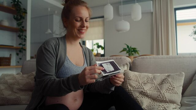 Pregnant woman sitting on sofa and browsing ultrasound images 