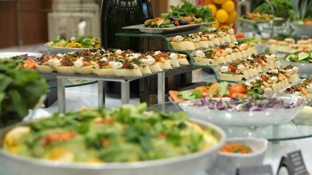 Close-up of a buffet table with canapes, vegetables and herbs in a restaurant. Close-up of canapes, vegetables and herbs on a banquet table.