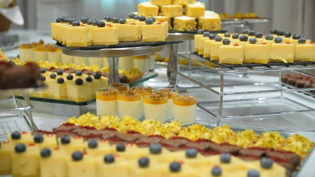 Close-up of waiter's hands in blue gloves laying out food on the buffet table in a restaurant. Waiter's hands laying out sweet dishes on the banquet table. A dessert table.