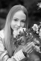 Black and white close-up portrait with a young cute girl, a flower near her face close. Enjoying the floral aroma. Beauty and youth concept