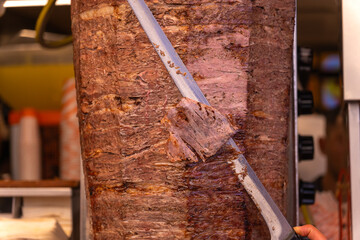 Close-up of a chef cutting meat with a doner knife for a traditional street food doner kebab or...