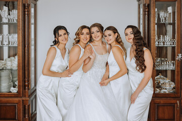 A beautiful bride and her bridesmaids are having fun in the morning. Wedding celebration. Happy girls at their best friend's wedding. A beautiful and elegant bride with her bridesmaids