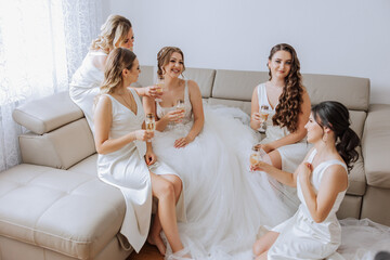 Photo bride with her friends drinking champagne from glasses. Cropped shot of a beautiful young...