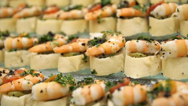 Close-up of canapes with shrimps, cherry tomatoes and herbs on a buffet table in a restaurant. Close-up of a buffet table with canapes, shrimps and herbs. Buffet food.