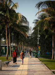 People walking along sidewalk in public park: Da Nang, Vietnam