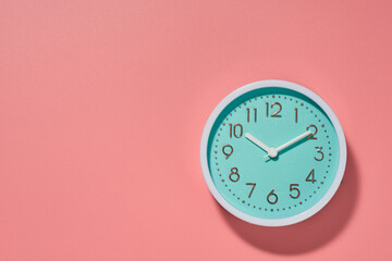 Round turquoise alarm clock on a pink background. Copy space. Top view.