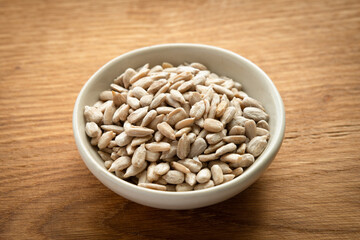 Bowl of peeled raw sunflower seeds on a wooden background. Low angle view.