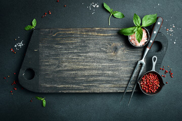 Cooking background, free space for text. Kitchen cutting board, spices and herbs. On a black stone...