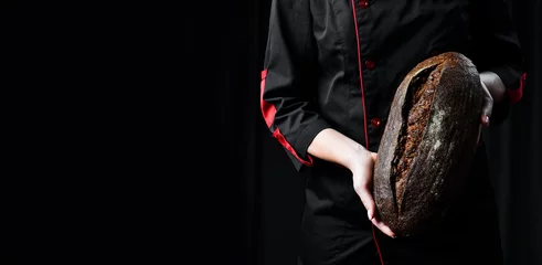 Fototapete Brot Fragrant black oval bread in female hands. Homemade rye bread.
