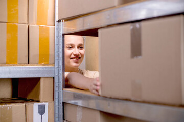 A woman packs boxes, puts the box on the rack. Delivery of goods. Packaging of goods in the warehouse