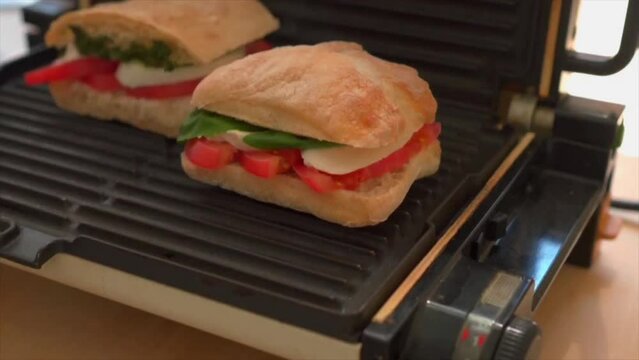 Placing homemade caprese panini sandwiches on panini maker