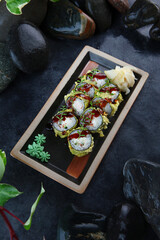 Tempura rolls with king prawns. Traditional Japanese food. Vertical photo on a black background. White ginger. Top view. Photo on black background with smoke.