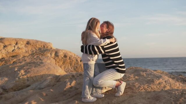 Slow motion, mother and daughter go to meet each other and hug against the background of the sea