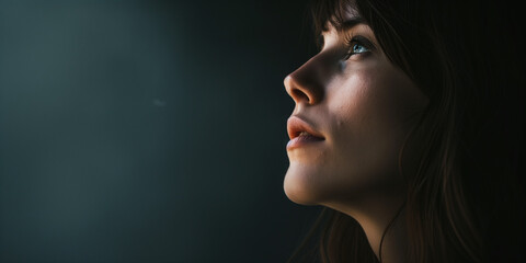 Contemplative young woman in profile, her features accentuated by striking contrast lighting
