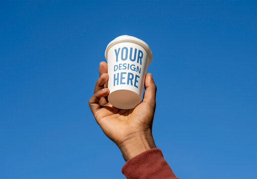 Mockup of man holding customizable cup against blue sky