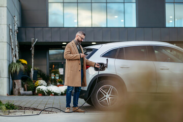 Man plugging in charging plug in electric car before going to shopping. Electric vehicle charging...