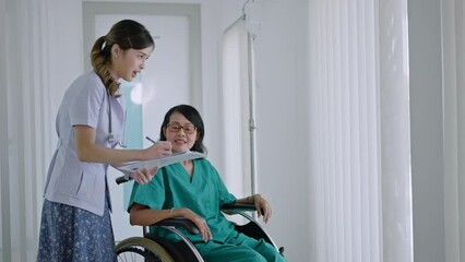 Asian doctor drive wheelchair and touch on shoulder of patient, doctor and old female talk about symptoms and treatment plan, rehabilitation activity, elderly healthcare promotion