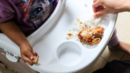 Fried chicken with rice placed on a white child's dining table, the food is placed without a plate. Examples of serving food that is less than hygienic.