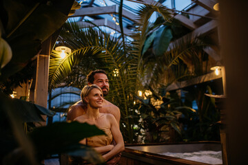 Beautiful couple standing in hotel greenhouse, enjoying romantic wellness weekend in spa. Concept...