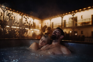 Beautiful mature couple relaxing in outdoor hot tub, enjoying romantic wellness weekend in spa. Concept of Valentine's Day. - obrazy, fototapety, plakaty