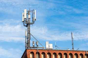 Antenne für den mobilen Funkverkehr auf dem Dach eines Gebäudes vor blauem Himmel