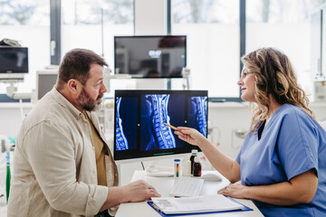 Doctor consulting with overweight patient, discussing test result and x-ray scans in doctor office....