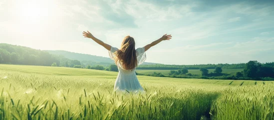 Foto op Canvas girl in green field with open arms dancing and enjoying nature. Creative Banner. Copyspace image © HN Works