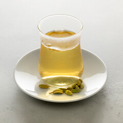 Tea glass with fresh made hot Cardamon tea and seed pods close up