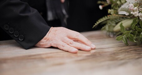 Death, funeral and hand on coffin in mourning, family at service in graveyard or church for...