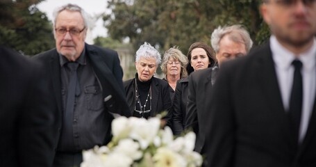 Pallbearers, men and walking with coffin in funeral, ceremony or mourning event at graveyard with...