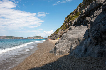 Fototapeta na wymiar Shingle and rocky beach of a nudist beach (FKK). Marina di Camerota, Italy.