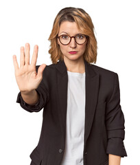 Caucasian woman in black business suit standing with outstretched hand showing stop sign, preventing you.