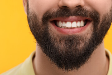 Obraz premium Man with clean teeth smiling on yellow background, closeup