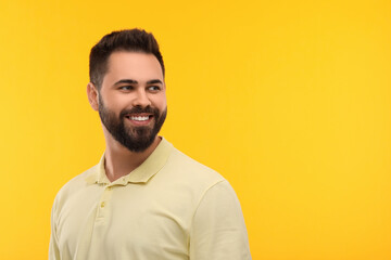 Obraz premium Man with clean teeth smiling on yellow background, space for text