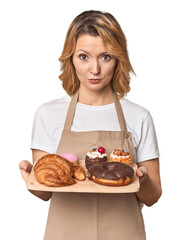 Caucasian middle-aged female baker with sweets tray in studio