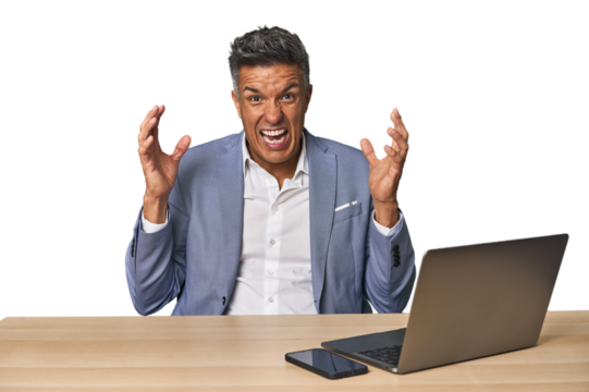 Elegant businessman at desk with laptop screaming to the sky, looking up, frustrated.