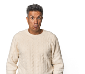 Middle-aged Latino man shrugs shoulders and open eyes confused.