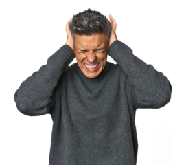 Middle-aged Latino man covering ears with hands trying not to hear too loud sound.
