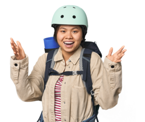 Chinese woman geared up for mountain activities receiving a pleasant surprise, excited and raising hands.